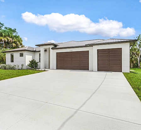 Newly paved concrete driveway leading to a modern white stucco home built by Ames Built in Southwest Florida.